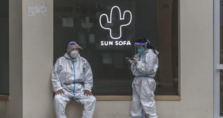 epa09935938 People in protective gear stand on the street amid the ongoing Covid-19 lockdown in Shanghai, China, 09 May 2022. Shanghai on 09 May reported a drop in Covid-19 cases, while the city has been under strict lockdown amid China's zero-Covid policy for six consecutive weeks. EPA/ALEX PLAVEVSKI/Alex Plavevski
