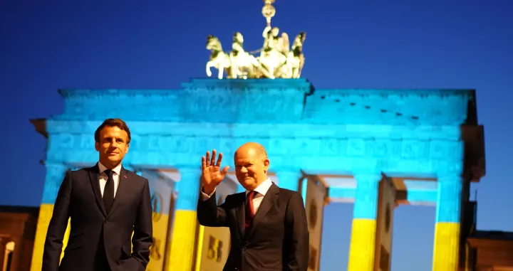epa09936738 German Chancellor Olaf Scholz (R) and French President Emmanuel Macron (L) pose for the media in front of the Brandenburg Gate, illuminated in the national colors of Ukraine, in Berlin, Germany, 09 May 2022. German Chancellor Olaf Scholz received French President Emmanuel Macron earlier at the Chancellery, where they announced, various buildings all over Europe will be illuminated in the Ukraine colors on Monday evening, among them, the Eiffel tower in Paris. EPA/CLEMENS BILAN/Clemens Bilan