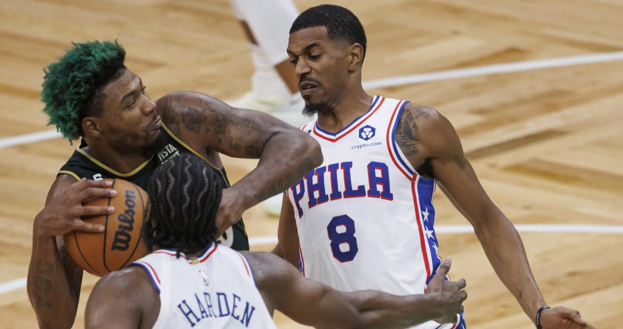 epa10251765 Boston Celtics guard Marcus Smart (L) hods onto the ball as Philadelphia 76ers guard James Harden (C) and Philadelphia 76ers guard De'Anthony Melton (R) defend during the third quarter at TD Garden in Boston, Massachusetts, USA, 18 October 2022. EPA/CJ GUNTHER SHUTTERSTOCK OUT