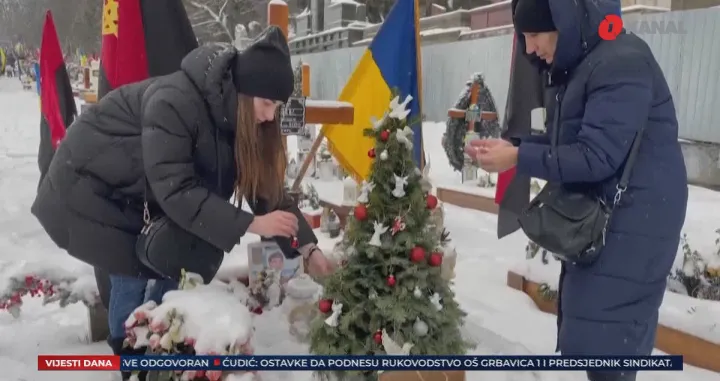 Supruga i majka palog vojnika kite jelku na grobu/