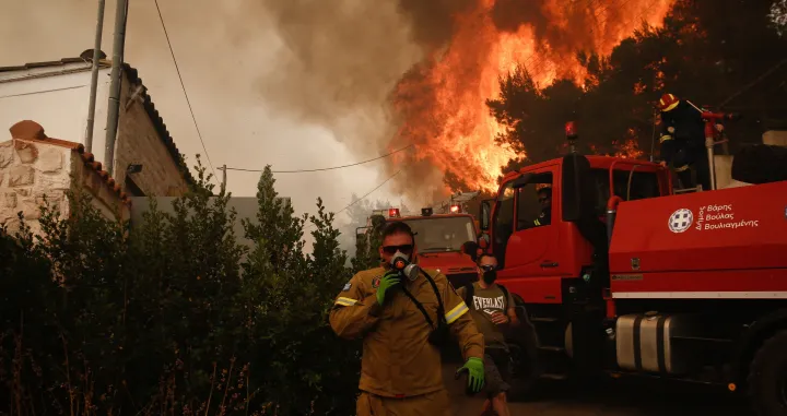 epa09995825 A fireman runs in front of flames rising behind him during a wildfire in the suburb of Voula, south of Athens, Greece, 04 June 2022. Greek authorities ordered a limited evacuation in the coastal suburb of Voula, southern Athens, as strong winds fanning a raging fire have changed its direction, threatening residential area. EPA/YANNIS KOLESIDIS/Yannis Kolesidis