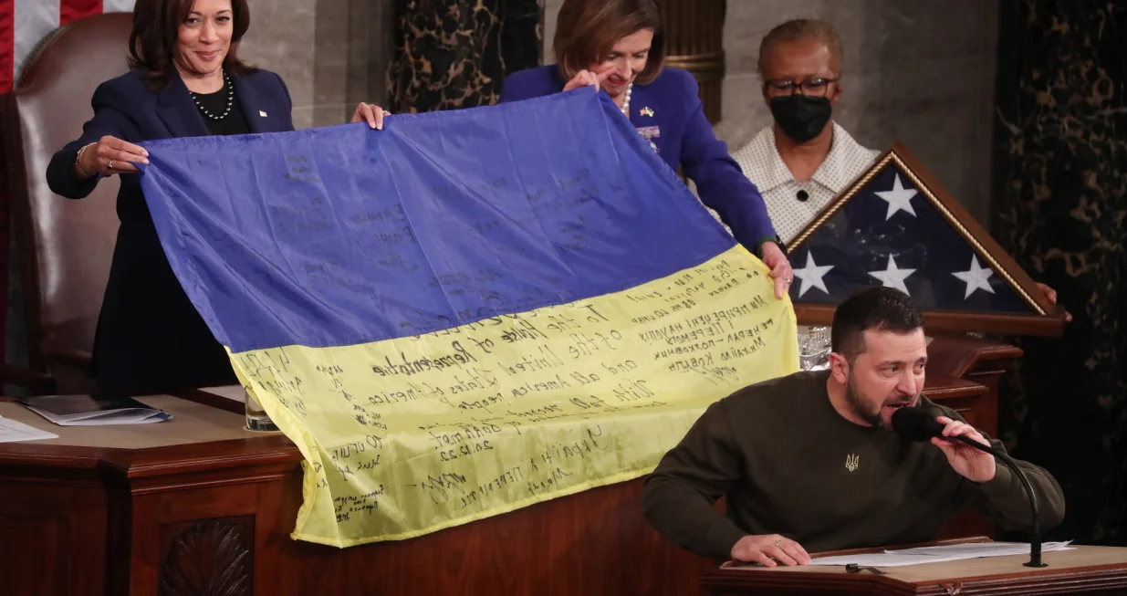 epa10376007 Speaker of the House Nancy Pelosi (C) and US Vice President Kamala Harris (L) hold a Ukrainian flag after Ukrainian President Volodymyr Zelensky delivered an address to a joint meeting of the United States Congress in the House of Representatives chamber on Capitol Hill in Washington DC, USA, 21 December 2022. Zelensky is on his first known foreign trip since Russia invaded Ukraine more than 300 days ago, travelling to the US on a high-stakes visit to secure support for his war effort. EPA/MICHAEL REYNOLDS/Michael Reynolds