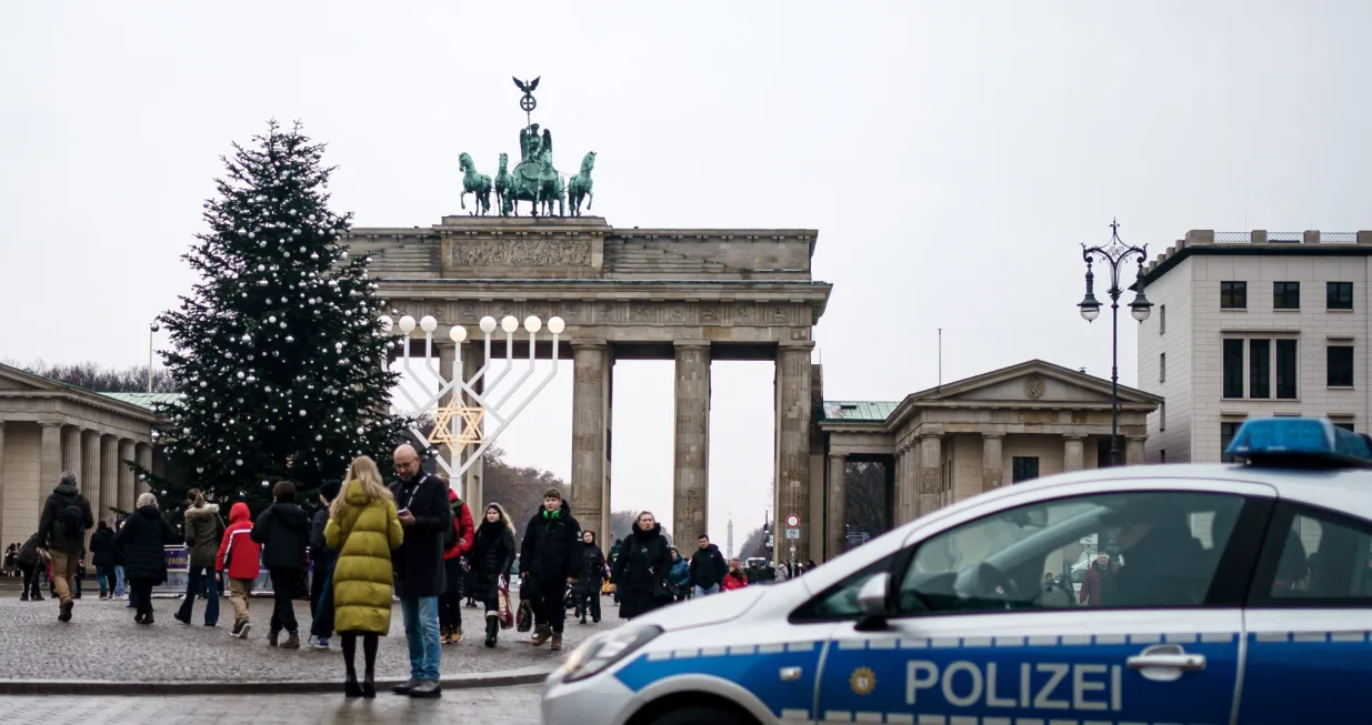 epa10375504 Police officers pictured at the Brandenburg Gate after environmental activists cut the top of the Christmas tree, Berlin, Germany, 21 December 2022. EPA/CLEMENS BILAN