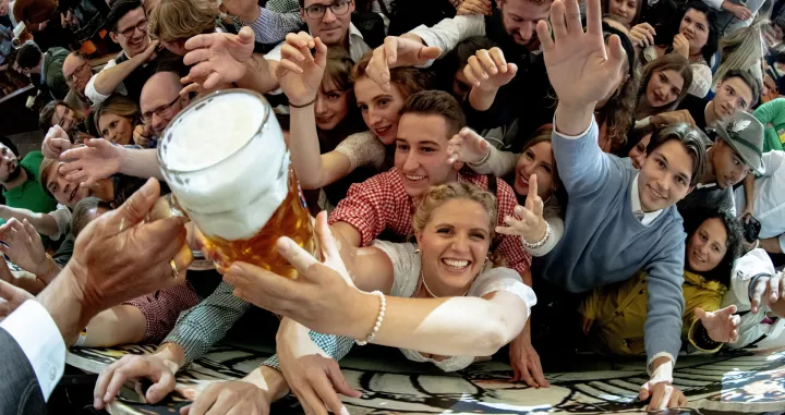 epa10189548 Visitors reach out for free beer in the Paulaner beer tent during the opening of the 187th edition of the traditional Oktoberfest beer and amusement festival in Bavaria's state capital of Munich, Germany, 17 September 2022. The Oktoberfest 2022 runs from 17 September to 03 October 2022 and several millions of visitors are expected from all over the world. The event resumes after being canceled for two years in a row due to the coronavirus disease (COVID-19) pandemic. EPA/CHRISTIAN BRUNA/Christian Bruna