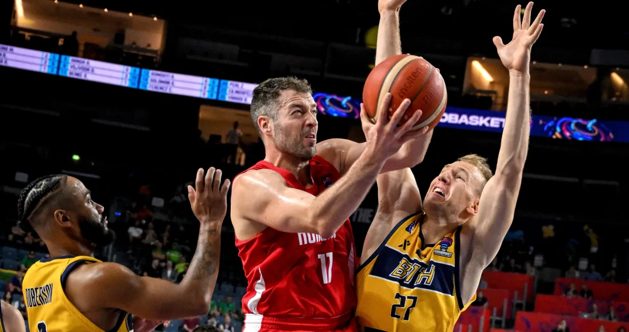 epa10152360 Szilard Benke of Hungary (C) in action against John Roberson (L) and Adin Vrabac (R) of Bosnia and Herzegovina during the FIBA EuroBasket 2022 group stage match between Bosnia and Herzegovina and Hungary in Cologne, Germany, 01 September 2022. EPA/SASCHA STEINBACH