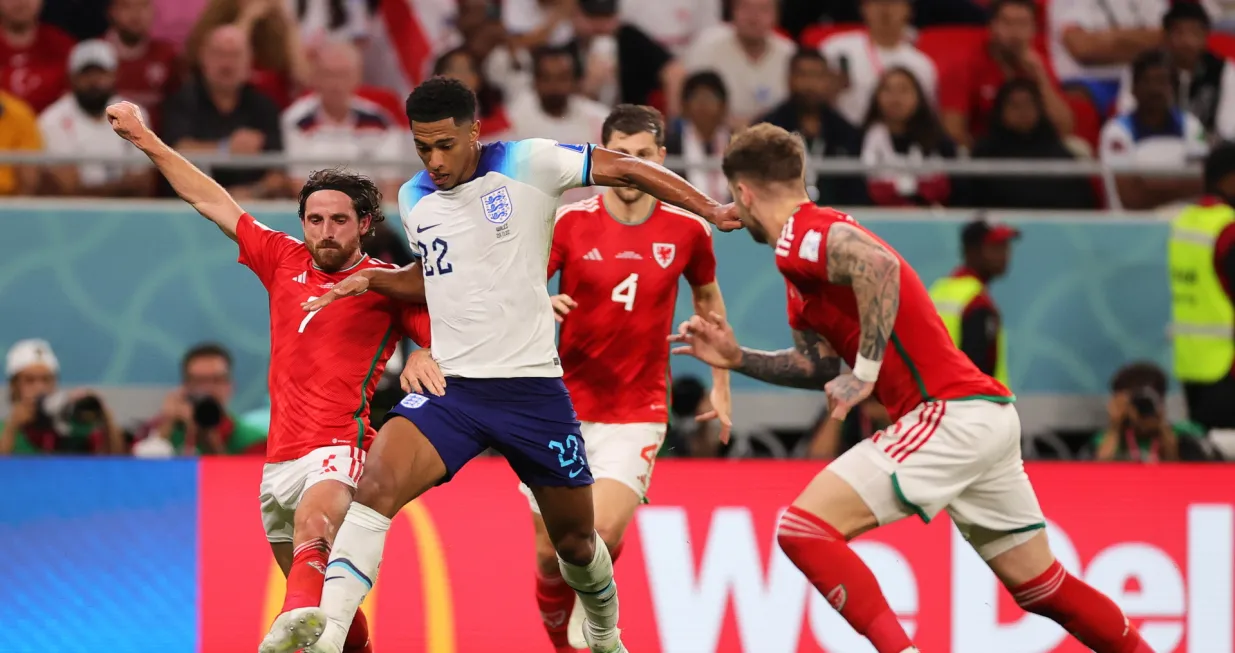 epa10337231 Jude Bellingham (C) of England in action against Joe Allen (L) of Wales during the FIFA World Cup 2022 group B soccer match between Wales and England at Ahmad bin Ali Stadium in Doha, Qatar, 29 November 2022. EPA/Friedemann Vogel