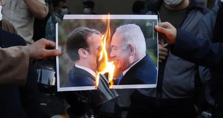 epa08780732 Iranians burn a picture depicting French President Emanuel Macron and Israel President Benjamin Netanyahu, during an anti-France protest demonstration in front of the French embassy&nbsp;in Tehran, Iran, 28 October 2020. Media reported that President Rouhani has condemned insulting to Prophet Muhammad and asked those who caused (referring to French President Emanuel Macron) this to apologize to Islam world. Macron&#039;s comments came after the recent beheading of a teacher in France after he had shown cartoons of the Prophet Muhammad in class. French President Macron vowed his country would not give up publishing such cartoons. EPA/ABEDIN TAHERKENAREH/Abedin Taherkenareh