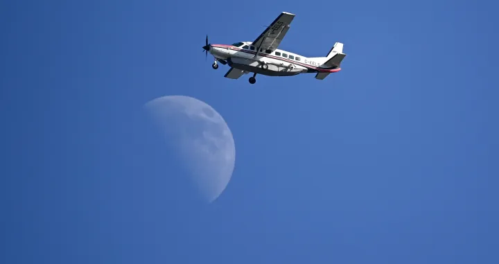 epa09351010 A Cessna 208B Grand Caravan Aircraft G-EELS fly's past the moon over the Royal St George's golf course during the 3rd round of The Open 2021 golf championship at in Sandwich, Kent, Britain, 17 July 2021. EPA/NEIL HALL/Neil Hall