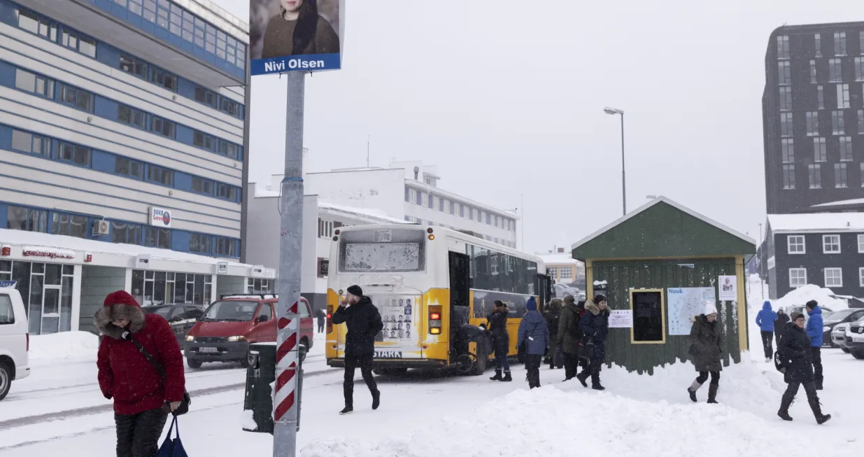 epa09098311 People walk as a campaign poster for Nivi Olsen of the Democrats Party is hung on a pole in Nuuk, Greenland, 25 March 2021. Greenland will hold parliamentary elections on 06 April 2021. EPA/Christian Klindt Soelbeck DENMARK OUT/Christian Klindt Soelbeck