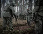 A Lithuanian instructor uses a tree branch as a pointer to demonstrate a plan, while Ukrainian soldiers observe./Nato