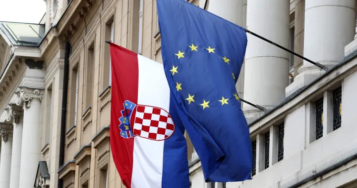 epa09960504 The flags of Croatia (L) and European Union (EU) hang from the facade of the Parliament building at old town in Zagreb, Croatia, 20 May 2022. Croatia, which joined the EU in 2013, is set to join the Eurozone in January 2023, with the introduction of the euro as the country's official currency after Croatian lawmakers voted in favor of legislation to bring the shared currency. EPA/ANTONIO BAT/Antonio Bat