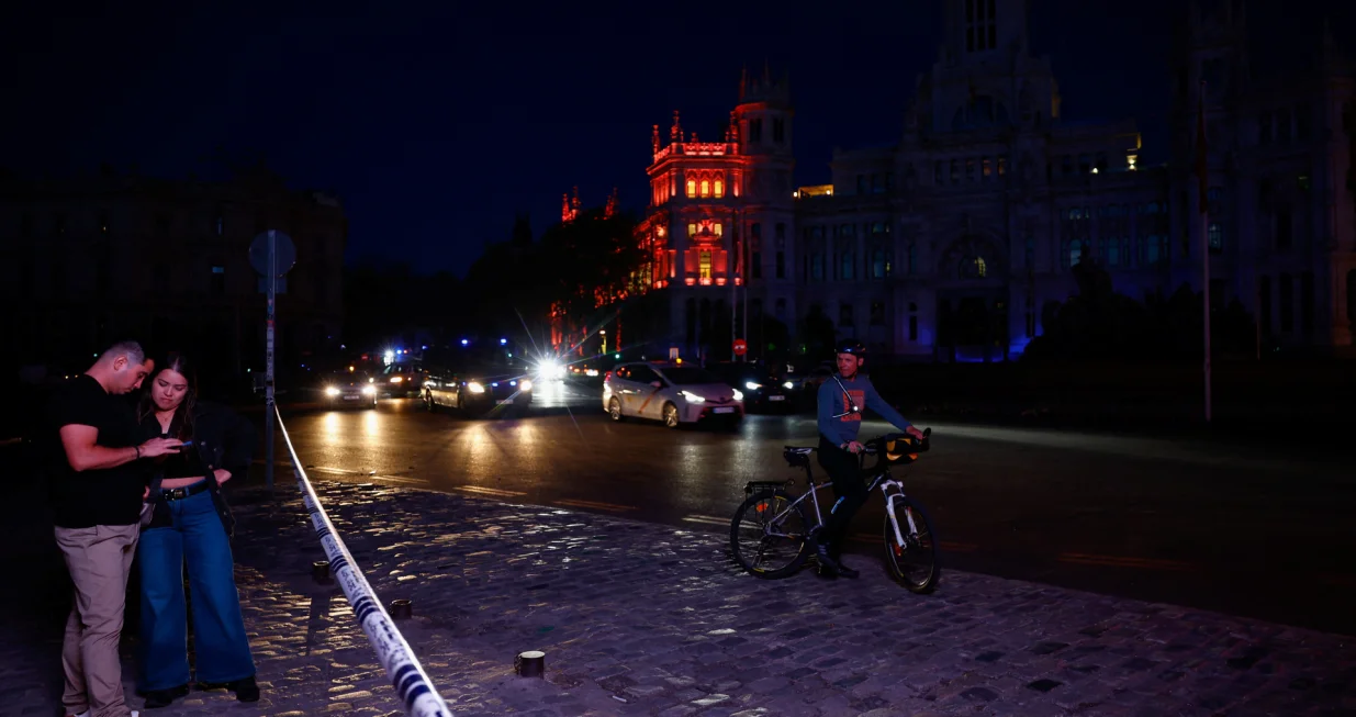 People check their mobile phones near the town hall building at Cibeles Square as some lights begin to come back on during a nationwide power outage in Madrid, Spain, April 28, 2025. REUTERS/Susana Vera/Susana Vera
