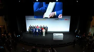 Incoming German Chancellor and leader of the Christian Democratic Union (CDU) Friedrich Merz holds the coalition government agreement between CDU, CSU and SPD, next to Christian Social Union (CSU) leader and Bavarian Premier Markus Soeder and Designated German Vice Chancellor and Designated Finance Minister Lars Klingbeil, at the Gasometer in Berlin, Germany May 5, 2025. REUTERS/Annegret Hilse/Annegret Hilse