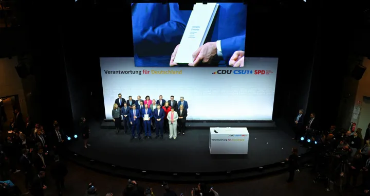 Incoming German Chancellor and leader of the Christian Democratic Union (CDU) Friedrich Merz holds the coalition government agreement between CDU, CSU and SPD, next to Christian Social Union (CSU) leader and Bavarian Premier Markus Soeder and Designated German Vice Chancellor and Designated Finance Minister Lars Klingbeil, at the Gasometer in Berlin, Germany May 5, 2025. REUTERS/Annegret Hilse/Annegret Hilse