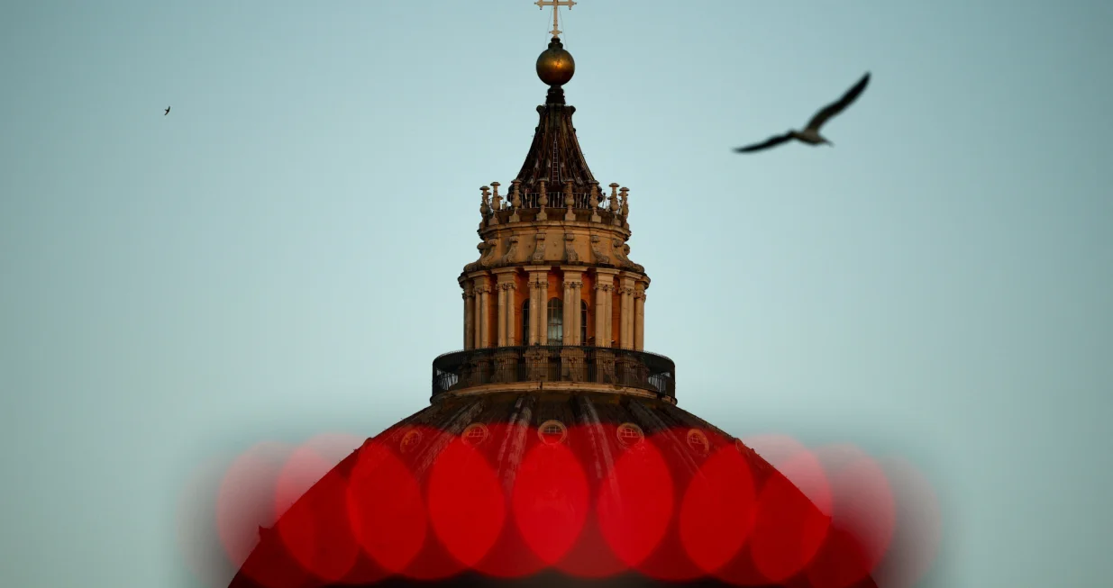 A bird flies past the dome of St. Peter's Basilica on the first day of the conclave to elect the next pope, near the Vatican, in Rome, Italy, May 7, 2025. REUTERS/Guglielmo Mangiapane  TPX IMAGES OF THE DAY/Guglielmo Mangiapane