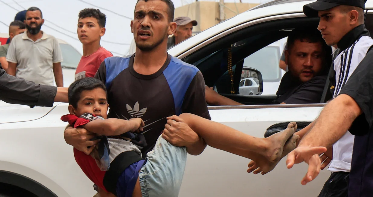 A Palestinian man carries a wounded person to Nasser hospital following an Israeli strike, in Khan Younis, southern Gaza Strip, May 15, 2025. REUTERS/Hatem Khaled/Hatem Khaled