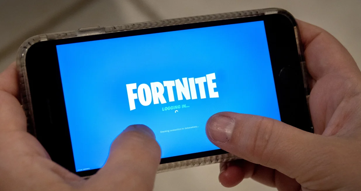 epa08621882 A person plays Fortnite on an iPhone in Miami, Florida, USA, 24 August 2020. US tech giant Apple and game developer Epic Games are in a dispute over the distribution of income from in-app purchases of the game Fortnite. EPA/CRISTOBAL HERRERA-ULASHKEVICH/Cristobal Herrera-ulashkevich