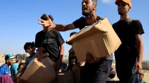 A person gestures as he carries a box as Palestinians gather near an aid distribution site run by the U.S.-backed Gaza Humanitarian Foundation, in Rafah, in the southern Gaza Strip, May 27, 2025. REUTERS/Hatem Khaled  TPX IMAGES OF THE DAY/Hatem Khaled