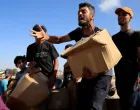 A person gestures as he carries a box as Palestinians gather near an aid distribution site run by the U.S.-backed Gaza Humanitarian Foundation, in Rafah, in the southern Gaza Strip, May 27, 2025. REUTERS/Hatem Khaled  TPX IMAGES OF THE DAY/Hatem Khaled