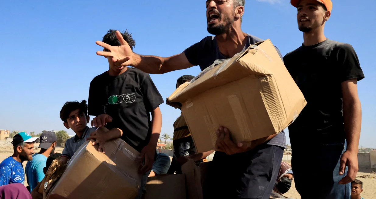 A person gestures as he carries a box as Palestinians gather near an aid distribution site run by the U.S.-backed Gaza Humanitarian Foundation, in Rafah, in the southern Gaza Strip, May 27, 2025. REUTERS/Hatem Khaled  TPX IMAGES OF THE DAY/Hatem Khaled