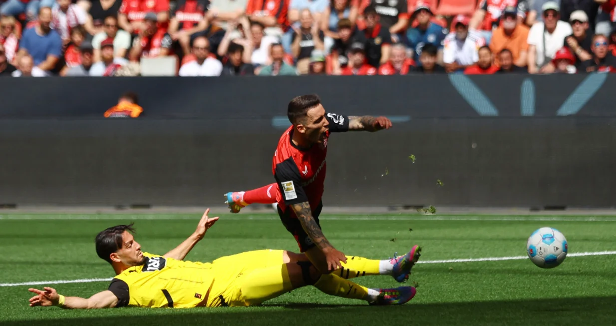 Soccer Football - Bundesliga - Bayer Leverkusen v Borussia Dortmund - BayArena, Leverkusen, Germany - May 11, 2025 Bayer Leverkusen's Alex Grimaldo is fouled by Borussia Dortmund's Ramy Bensebaini, decision of penalty later overturned by VAR REUTERS/Thilo Schmuelgen DFL REGULATIONS PROHIBIT ANY USE OF PHOTOGRAPHS AS IMAGE SEQUENCES AND/OR QUASI-VIDEO.