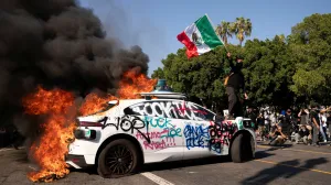 FILE PHOTO: SENSITIVE MATERIAL. THIS IMAGE MAY OFFEND OR DISTURB A person waves a Mexican flag atop a burning vehicle during a protest against federal immigration sweeps in downtown Los Angeles, California, U.S. June 8, 2025. REUTERS/David Ryder/File Photo/David Ryder