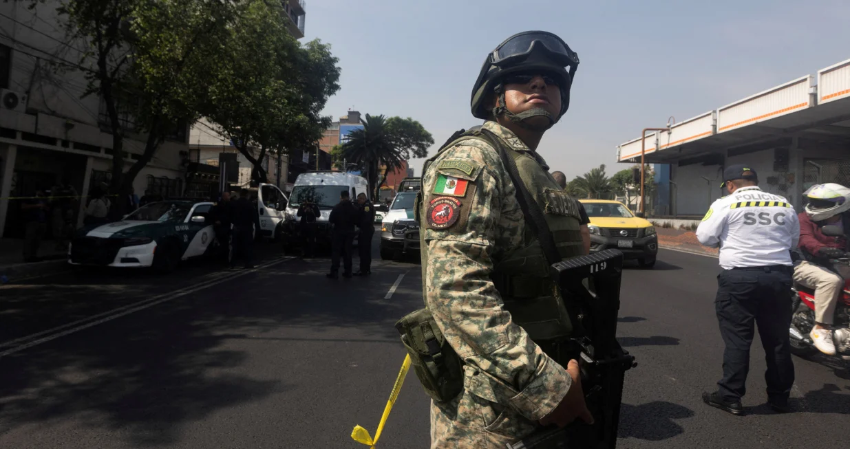FILE PHOTO: A member of the army stands guard, as police officers work at the scene, after two top members of Mexico City Mayor Clara Brugada's team were killed in what Mexican President Claudia Sheinbaum said was a direct attack, in Mexico City, Mexico, May 20, 2025. Picture partially taken through glass. REUTERS/Quetzalli Nicte-Ha/File Photo/Quetzalli Nicte-ha