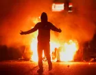 Fire burns near a demonstrator as riots continue in Ballymena, Northern Ireland, June 11, 2025. REUTERS/Clodagh Kilcoyne  TPX IMAGES OF THE DAY/Clodagh Kilcoyne