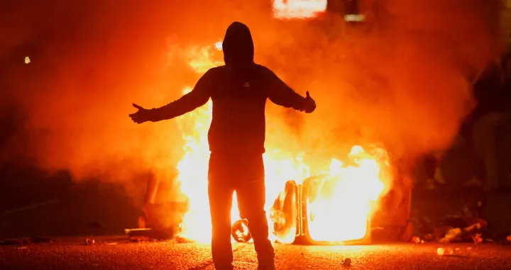 Fire burns near a demonstrator as riots continue in Ballymena, Northern Ireland, June 11, 2025. REUTERS/Clodagh Kilcoyne  TPX IMAGES OF THE DAY/Clodagh Kilcoyne