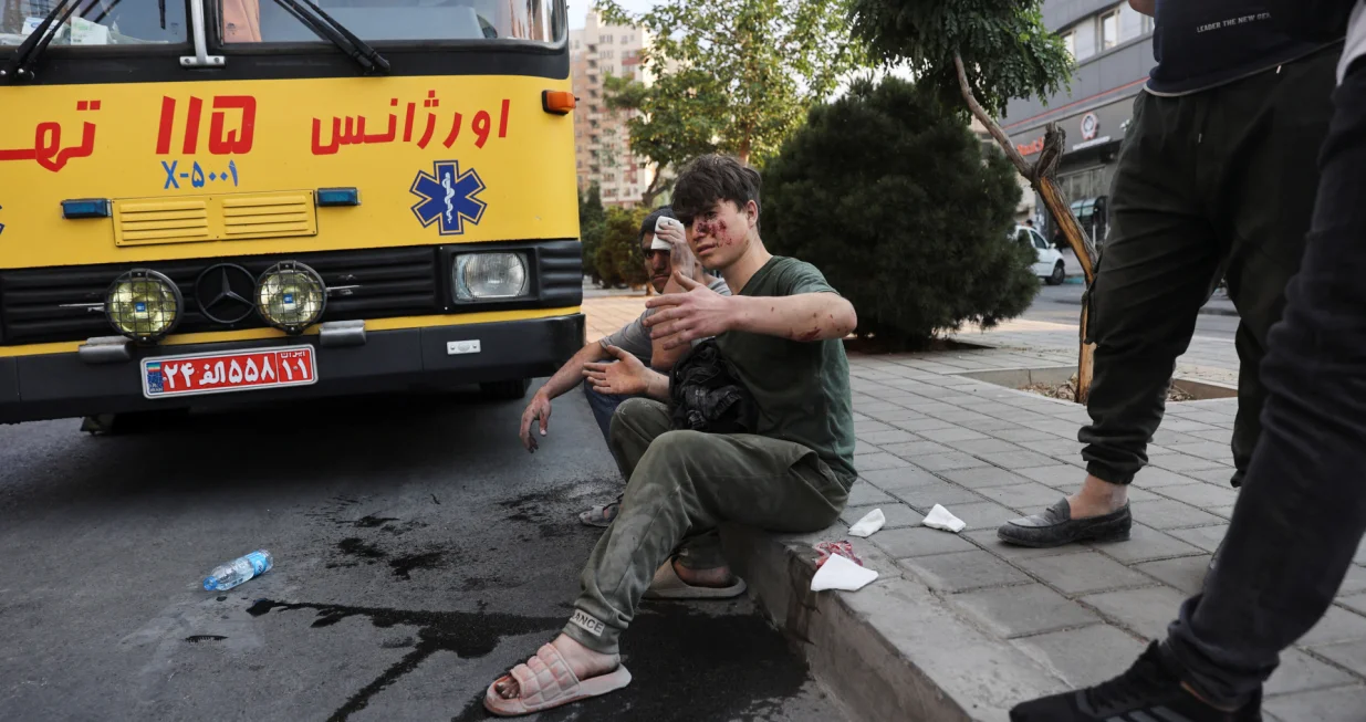 An injured person sits on a roadside in the aftermath of Israeli strikes, in Tehran, Iran, June 13, 2025. Majid Asgaripour/WANA (West Asia News Agency) via REUTERS ATTENTION EDITORS - THIS PICTURE WAS PROVIDED BY A THIRD PARTY  TPX IMAGES OF THE DAY/Majid Asgaripour