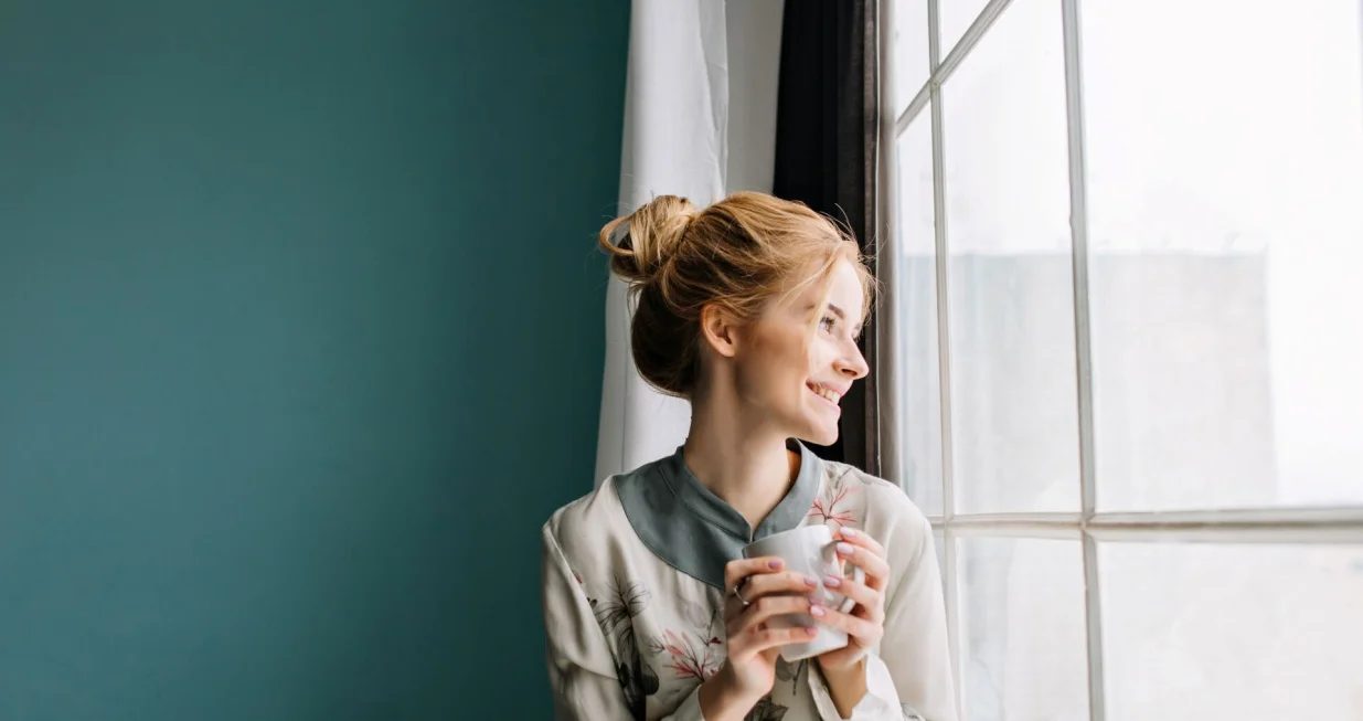 Djevojka pije čaj na prozoru//