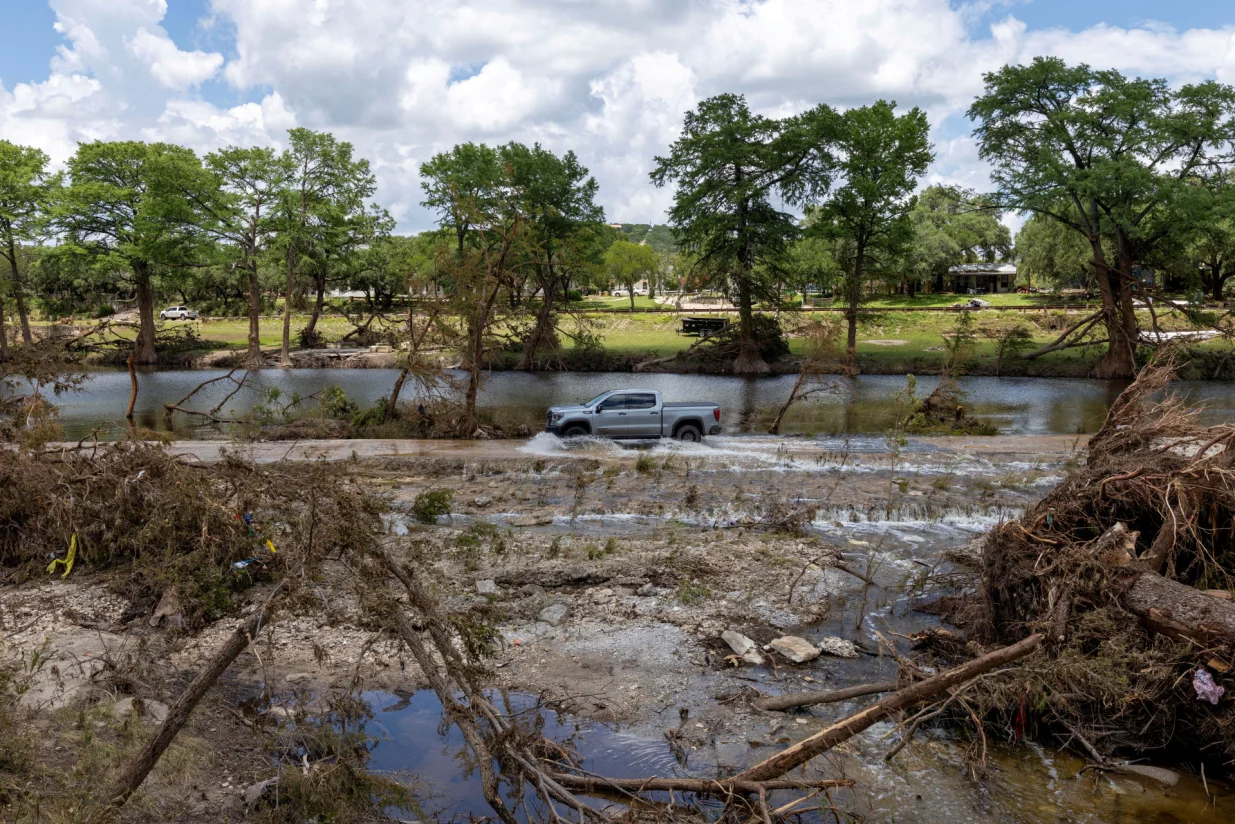 A vehicle drives through a road flooded by the waters of the Guadalupe River, in Hunt, Texas, U.S. July 9, 2025. REUTERS/Umit Bektas  TPX IMAGES OF THE DAY  REFILE - REMOVING MENTION OF "CAMP MYSTIC"./Umit Bektas