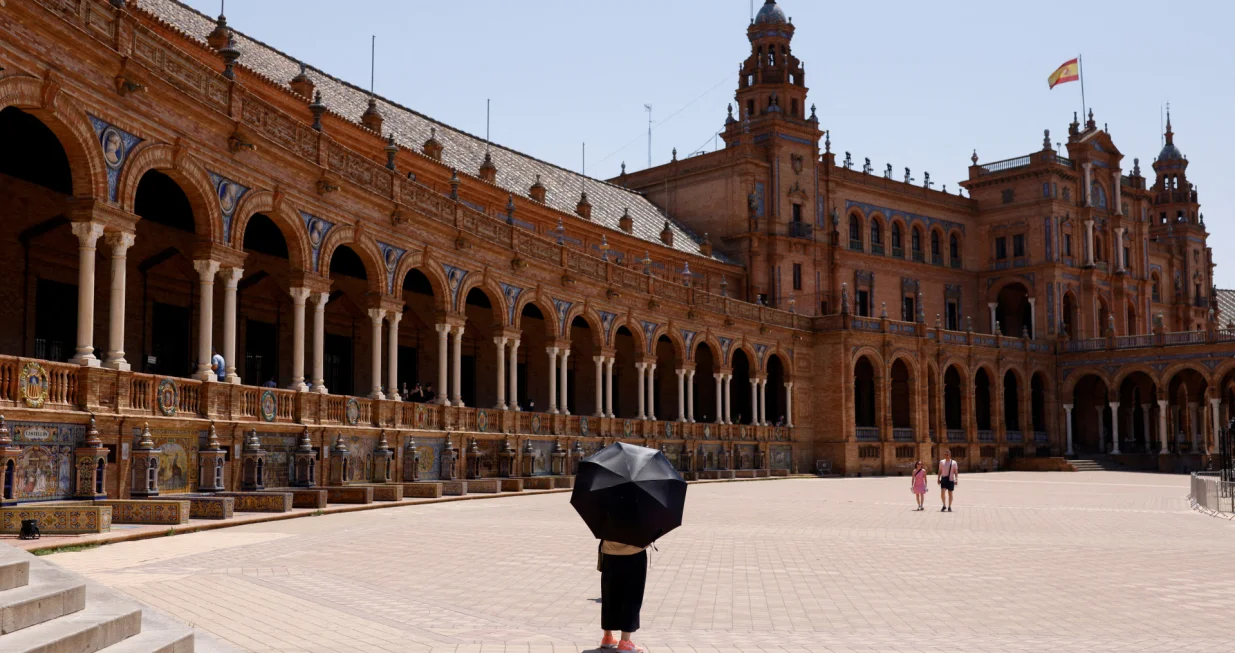 A woman uses an umbrella to protect herself from the sun during a heatwave in Seville, Spain, July 1, 2025. REUTERS/Marcelo del Pozo  TPX IMAGES OF THE DAY/Marcelo Del Pozo