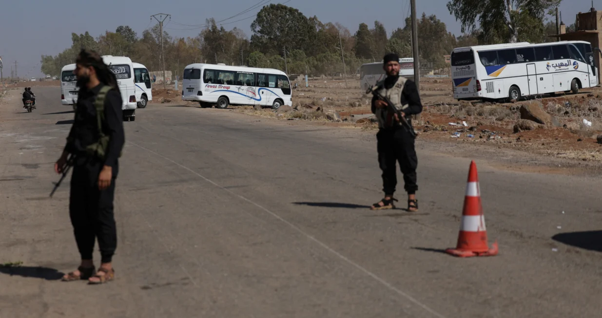 Internal Security Forces stand guard at a checkpoint as busses arrive for Syrian Arab Red Crescent's evacuation of civilians from Sweida, as part of an agreement between the Syrian government and Druze militants, in the Busra al-Harir area, Deraa Governorate, Syria July 23, 2025. REUTERS/Khalil Ashawi/Khalil Ashawi