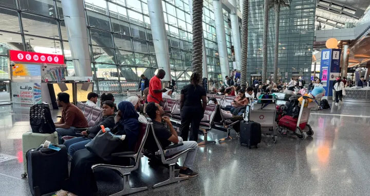 FILE PHOTO: People sit at Hamad International Airport after Qatar reopened its airspace following a brief closure in the wake of Iran's missile attack on Al Udeid Air Base on Monday, in Doha, Qatar, June 24, 2025. REUTERS/Stringer/File Photo/Stringer