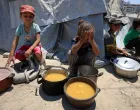 Palestinian children react near pots of food from a charity kitchen, amid a hunger crisis, in Gaza City, July 25, 2025. REUTERS/Dawoud Abu Alkas/Dawoud Abu Alkas