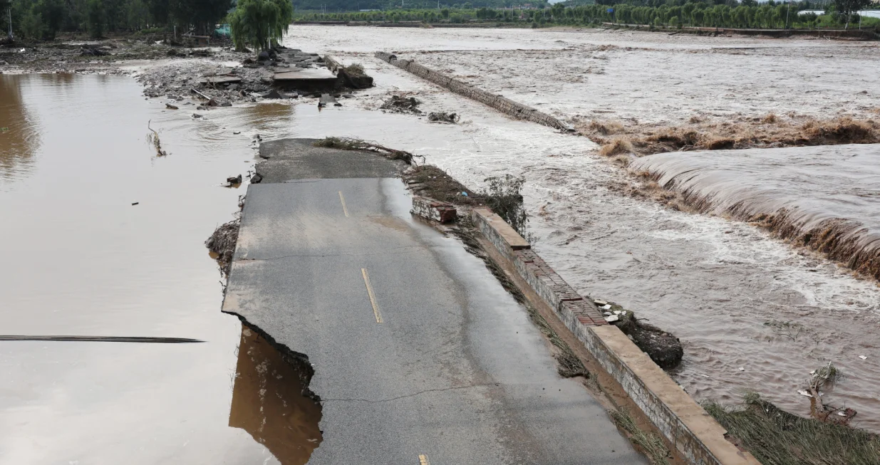 A general view of a damaged road next to the swollen Qingshui river, after a heavy rainfall flooded the area in Miyun district of Beijing, China July 28, 2025. REUTERS/Florence Lo/Florence Lo