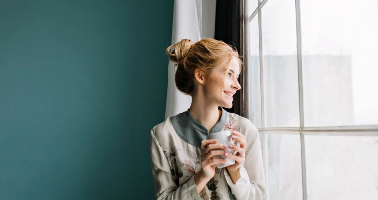 Djevojka pije čaj na prozoru//