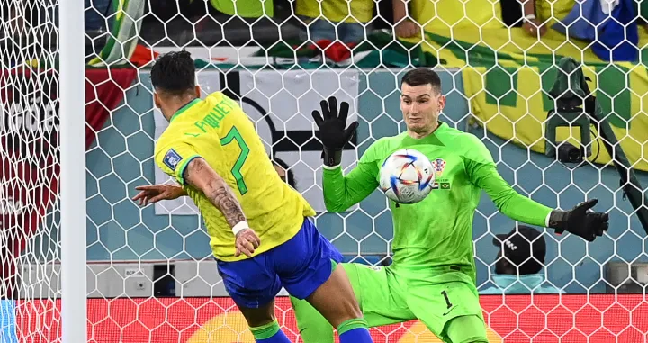 epa10357231 Lucas Paqueta (L) of Brazil in action against Croatia's goalkeeper Dominik Livakovic (R) during the FIFA World Cup 2022 quarter final soccer match between Croatia and Brazil at Education City Stadium in Doha, Qatar, 09 December 2022. EPA/Georgi Licovski
