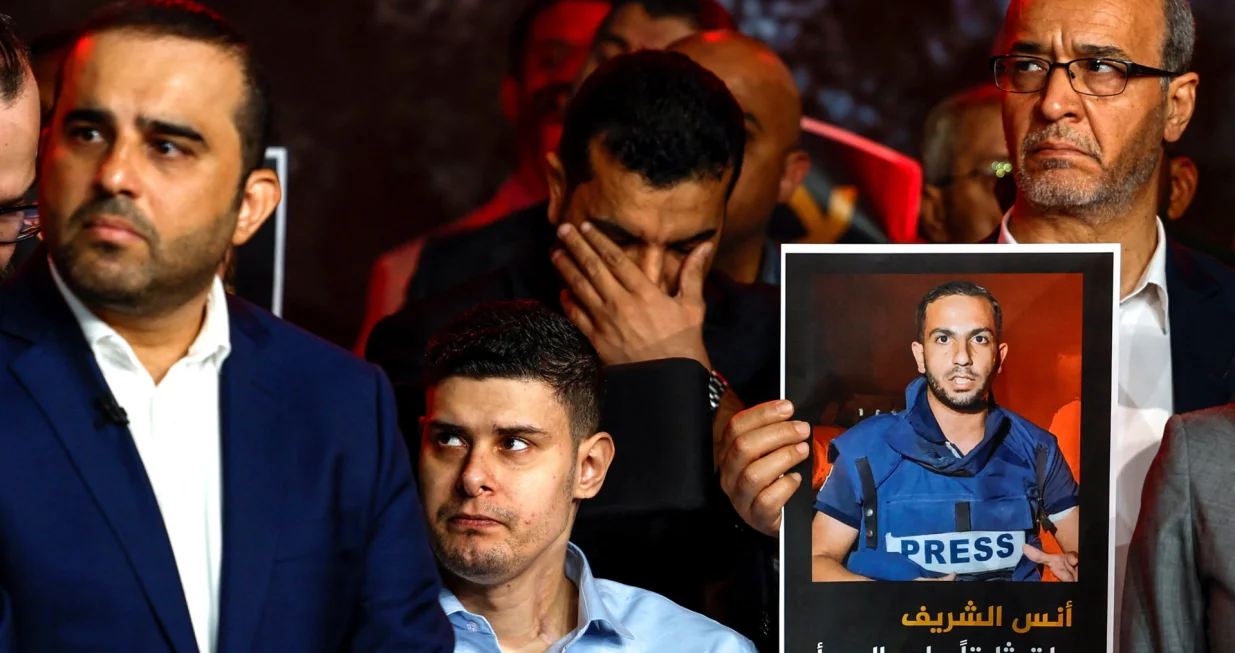 A person holds a placard with a picture of Anas Al Sharif, as Al Jazeera staff members gather at the network's studios to remember him, Mohammed Qreiqeh, Ibrahim Zaher, Mohammed Noufal and another colleague, who were killed in Gaza City by an Israeli strike, in Doha, Qatar, August 11, 2025. REUTERS/Ibraheem Abu Mustafa/Ibraheem Abu Mustafa