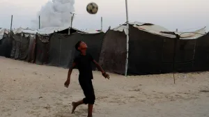 Palestinski dječak igra fudbal dok se dim diže nakon izraelskog napada u Khan Younisu/REUTERS/Foto: Hatem Khaled