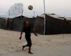Palestinski dječak igra fudbal dok se dim diže nakon izraelskog napada u Khan Younisu/REUTERS/Foto: Hatem Khaled