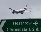 FILE PHOTO: A British Airways passenger plane flies over a road direction sign as it makes its landing approach to Heathrow Airport in west London, Britain, January 28, 2025. REUTERS/Toby Melville/File Photo/Toby Melville