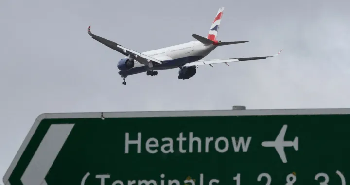 FILE PHOTO: A British Airways passenger plane flies over a road direction sign as it makes its landing approach to Heathrow Airport in west London, Britain, January 28, 2025. REUTERS/Toby Melville/File Photo/Toby Melville