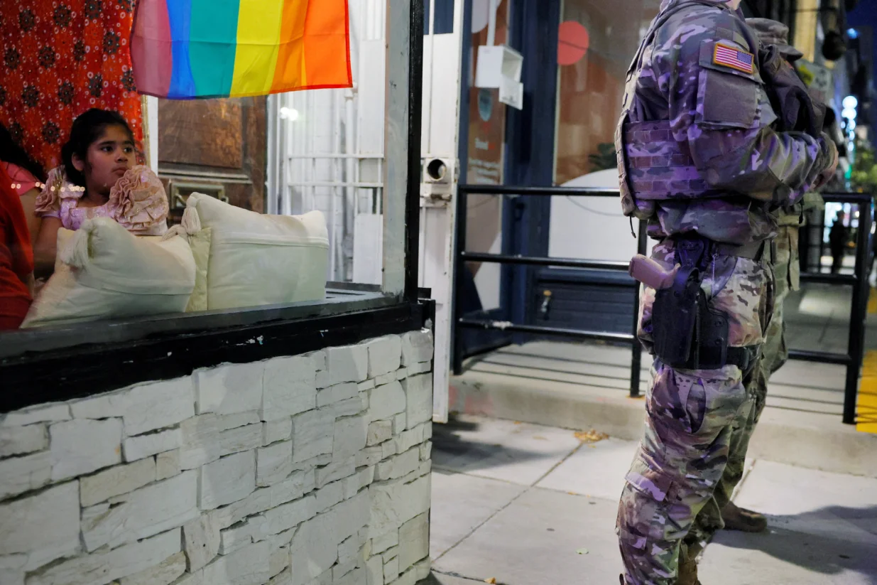 A girl having dinner with her family in a restaurant looks out at members of the Ohio National Guard, wearing their sidearms, weeks after U.S. President Donald Trump ordered National Guard and law enforcement to patrol the nation's capital to assist in crime prevention, in the Logan Circle neighborhood of Washington, D.C., U.S., August 24, 2025. REUTERS/Brian Snyder  TPX IMAGES OF THE DAY/Brian Snyder