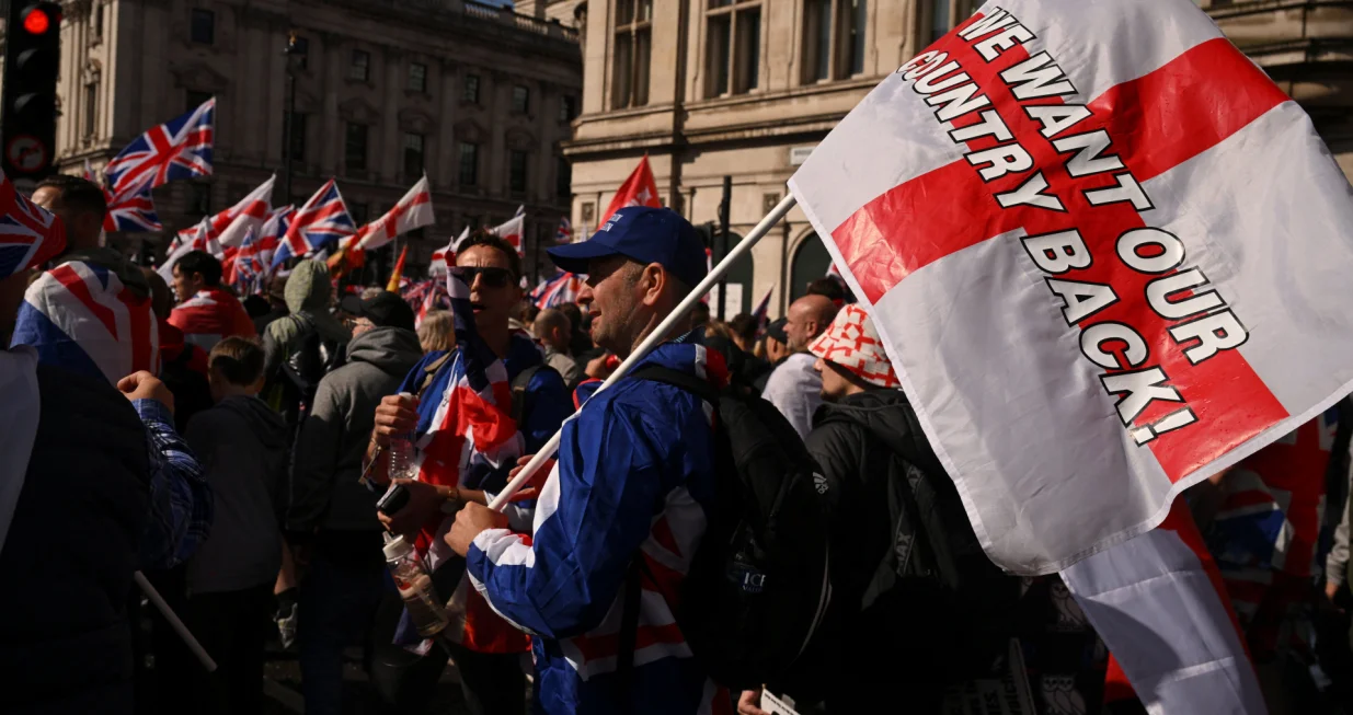 A man holds a flag that reads "We want our country back," as protesters gather on the day of an anti-immigration rally organised by British anti-immigration activist Stephen Yaxley-Lennon, also known as Tommy Robinson, in London, Britain, September 13, 2025. REUTERS/Jaimi Joy/Jaimi Joy