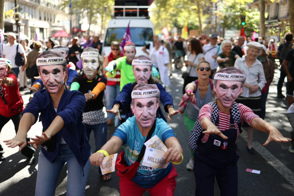 Protesters wearing masks depicting Bernard Arnault, Chairman and CEO of LVMH Moet Hennessy Louis Vuitton, dance during a demonstration in Paris as part of a day of nationwide strikes and protests against the government and cuts in the next budget, with supporters of the "Bloquons Tout" (Let's Block Everything) movement, France, September 18, 2025. The slogan reads "Fiscal fitness". REUTERS/Tom Nicholson/Tom Nicholson