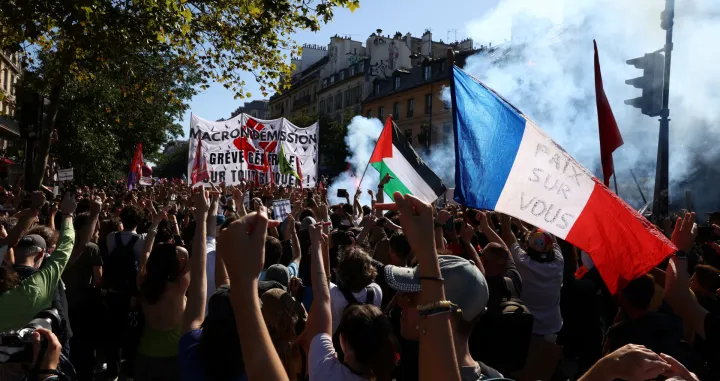 A protester holds a French national flag with the slogan "Peace on you" during a demonstration in Paris as part of a day of nationwide strikes and protests against the government and cuts in the next budget, with supporters of the "Bloquons Tout" (Let's Block Everything) movement, France, September 18, 2025. REUTERS/Tom Nicholson/Tom Nicholson