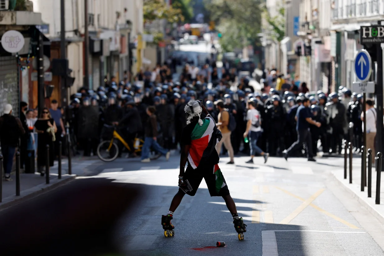 A protester wearing a Palestinian flag stands in front of French CRS riot police on position in a street during a demonstration in Paris as part of a day of nationwide strikes and protests against the government and cuts in the next budget, with supporters of the "Bloquons Tout" (Let's Block Everything) movement, France, September 18, 2025. REUTERS/Stephanie Lecocq/Stephanie Lecocq