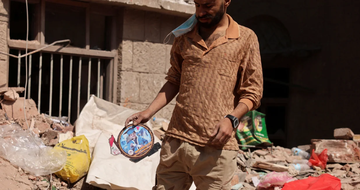 A man holds a picture of a boy as he stand at the site of a house destroyed in Wednesday's Israeli airstrikes in Sanaa, Yemen September 13, 2025. REUTERS/Khaled Abdullah/Khaled Abdullah